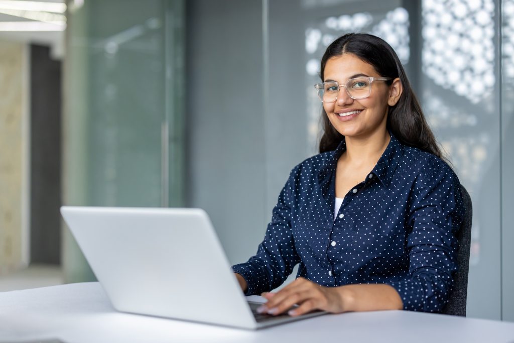young businesswoman smiling and working on laptop in modern office